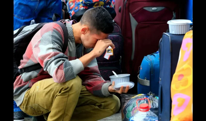 Un venezolano toma un refrigerio a la espera de cruzar el paso fronterizo entre Ecuador y Perú. Foto: EFE