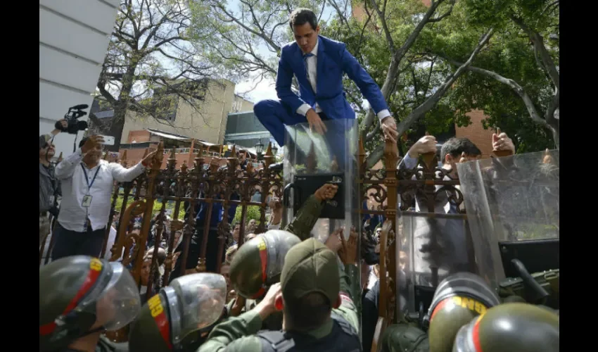 El presidente de la Asamblea Nacional, Juan Guaidó, líder de la oposición de Venezuela, trepa la valla en un intento fallido de ingresar al complejo de la Asamblea, ya que él y otros legisladores de la oposición no pueden ingresar a una sesión para elegir un nuevo liderazgo de la Asamblea en Caracas, Venezuela, el domingo, enero. .5, 2020. Con Guaido atrapado afuera, una lista rival encabezada por el legislador Luis Parra se juramentó como líderes de la legislatura de una sola cámara. (Foto AP / Matias Dela