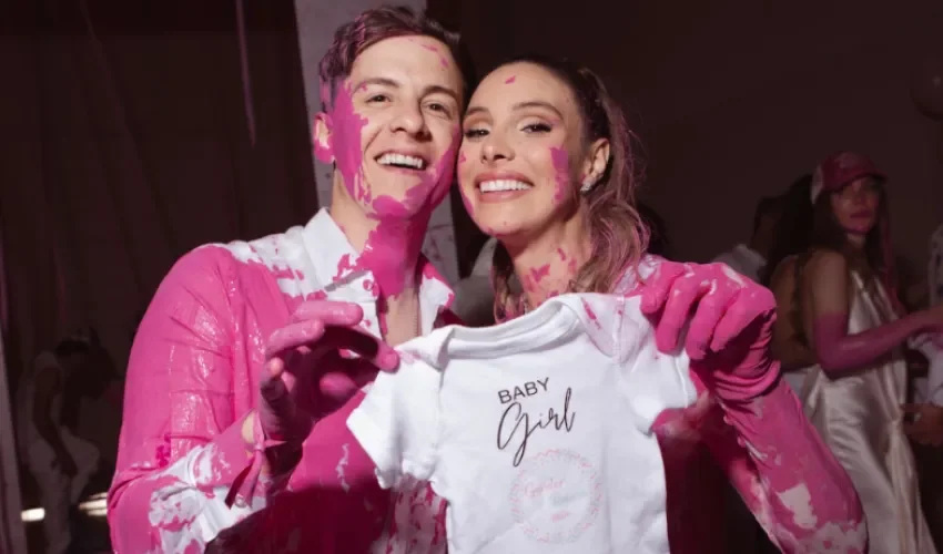 Fotografía cedida por EB Public Relations donde aparece la venezolana Lele Pons y el puertorriqueño Guaynaa manchados de color rosa y sosteniendo un vestido infantil de niñas durante la fiesta de revelación del sexo de su bebé