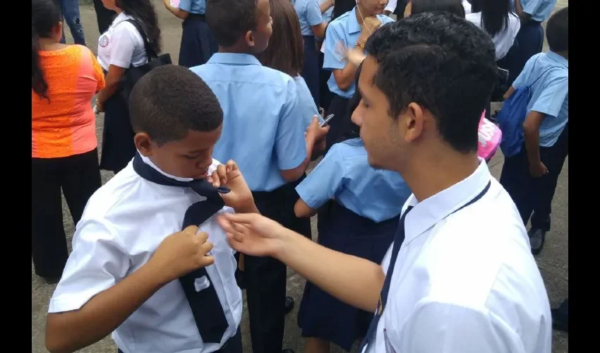 Este estudiante enseña a su compañero de la escuela Elena Chávez de Pinate a hacer el nudo de la corbata. Foto: Roberto Barrios
