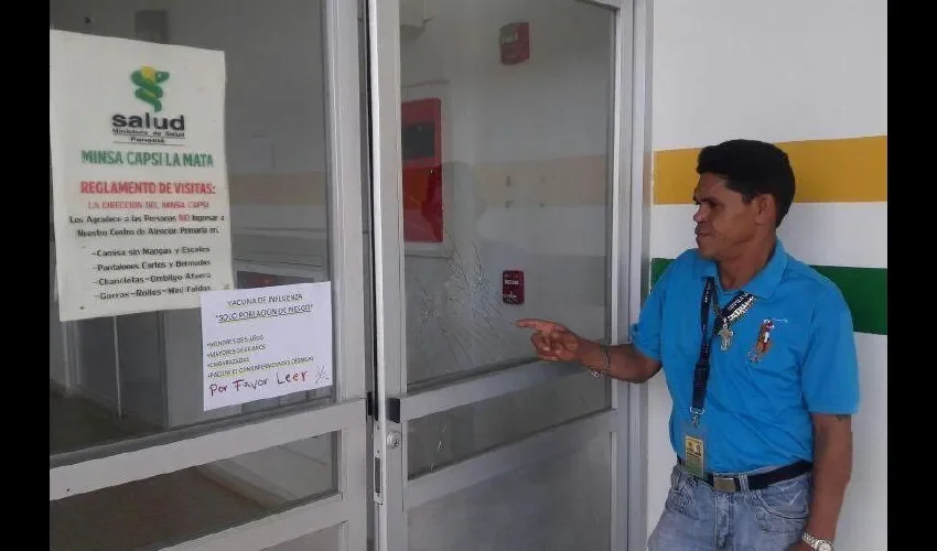 Un funcionario muestra el vidrio de la puerta que fue roto durante la desesperación de la gente. José Manuel Adames 