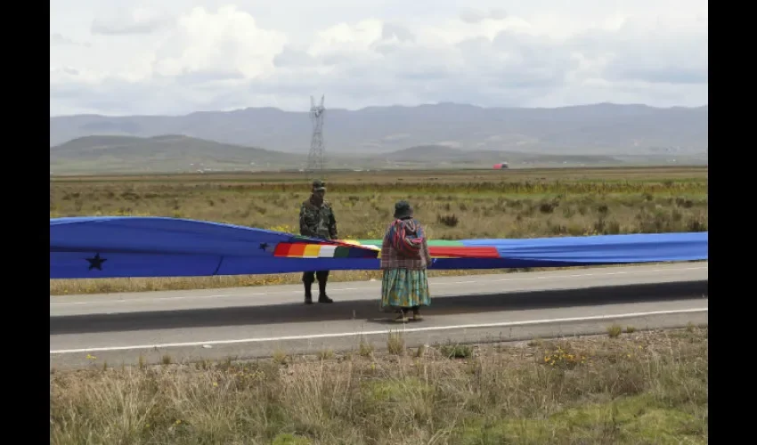 Indígenas aimaras y militares bolivianos, resguardan la bandera desplegada. FOTO/EFE