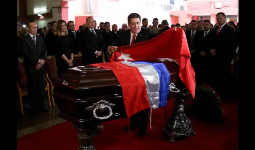 El presidente paraguayo, Horacio Cartes, coloca una bandera sobre el féretro de Gneiting. Foto: EFE
