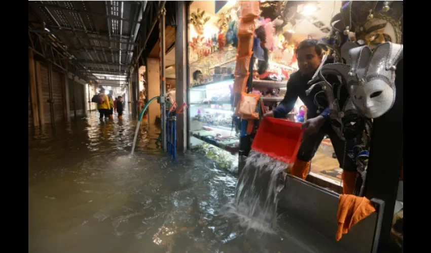 Un tendero achica agua de su tienda en Venecia tras las inundaciones. Foto: EFE
