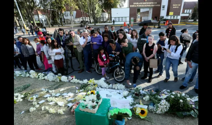 Decenas de personas llevan flores y prenden velas este viernes en honor a los policías fallecidos en el ataque. Foto: EFE