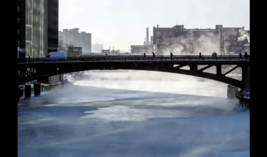 Varias personas cruzan un puente mientras la niebla se eleva desde el río Chicago. Foto: EFE