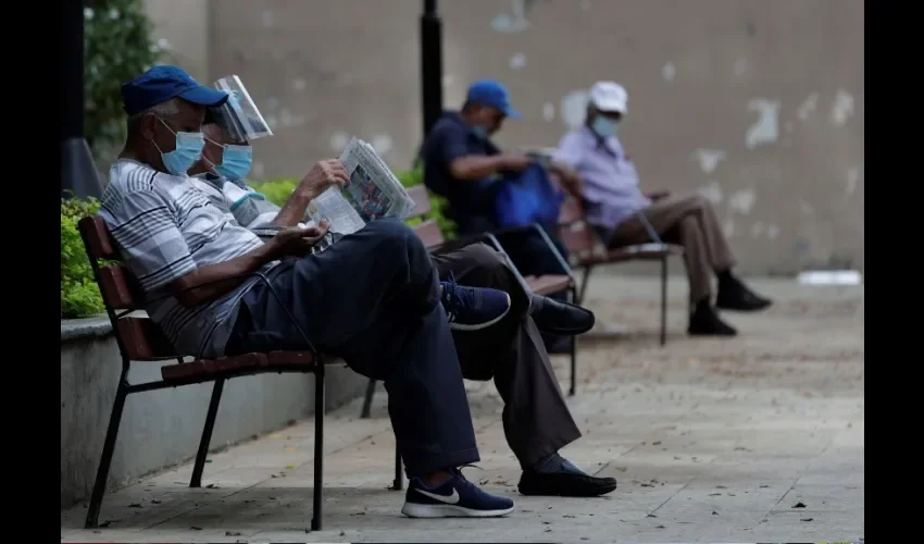 Personas leen periódicos en el parque de Santa Ana este lunes en la ciudad de Panamá (Panamá). EFE/Bienvenido Velasco