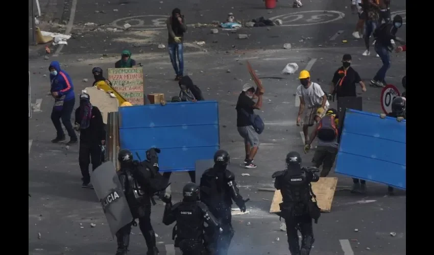  Manifestantes se enfrentan con miembros del Escuadrón Móvil Antidisturbios (ESMAD) durante las protestas hoy en Cali (Colombia). Foto: EFE. 