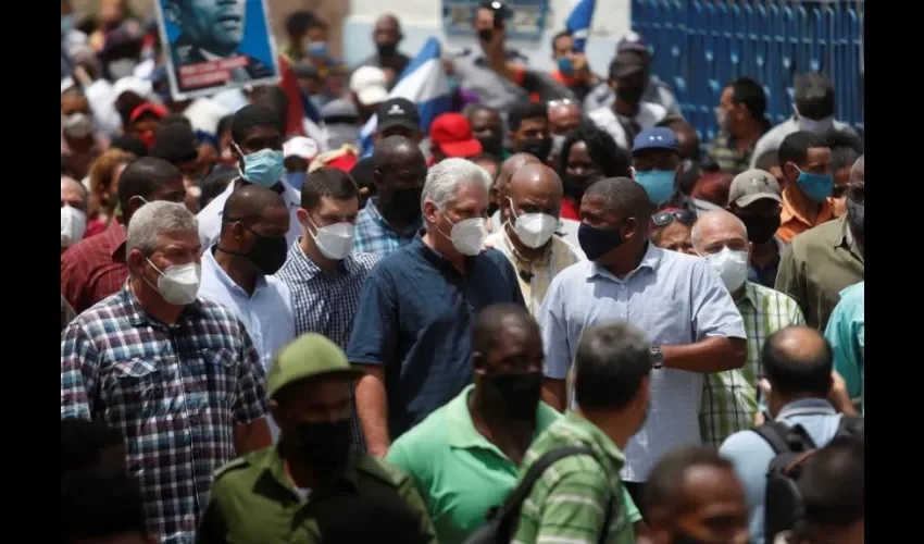 Presidente de Cuba Miguel Díaz-Canel (c) camina acompañado por simpatizantes hoy, por una calle del pueblo San Antonio de los Baños. Foto: EFE.  