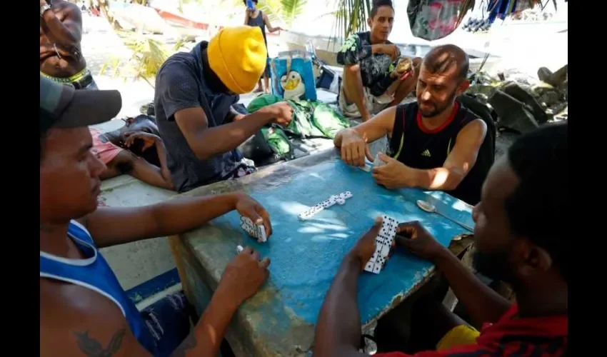 Migrantes haitianos y venezolanos juegan dominó hoy, en Necoclí (Colombia). Foto: EFE. 