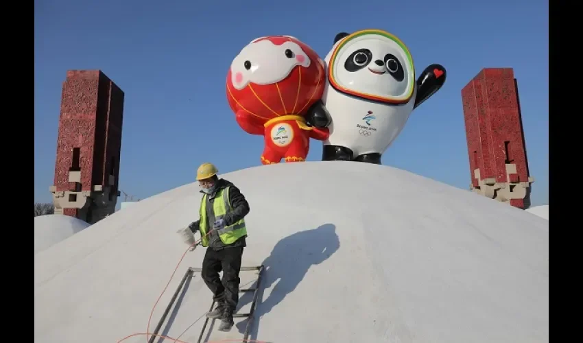Un operario pinta junto a las mascotas de los Juegos Olímpicos de Invierno Beijing 2022. Foto: EFE