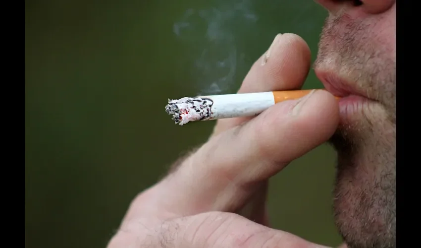 Una persona mientras se fuma un cigarrillo. 