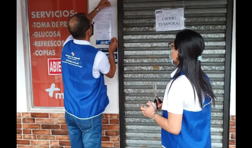 Momento en que el personal de salud coloca el letrero de cierre temporal. 