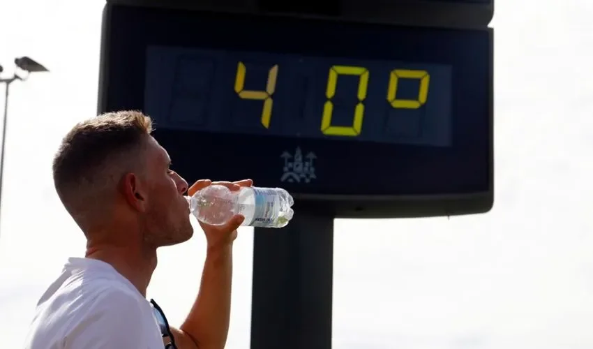 Un joven bebe agua junto a un termómetro de calle que marca 40 grados en el centro de Córdoba. EFE / Salas