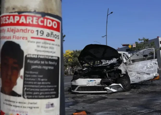  Fotografía que muestra un cartel de una persona desaparecida y un vehículo incendiado, este 22 de febrero de 2026, en una vía de Guadalajara (México). EFE/ Francisco Guasco 
